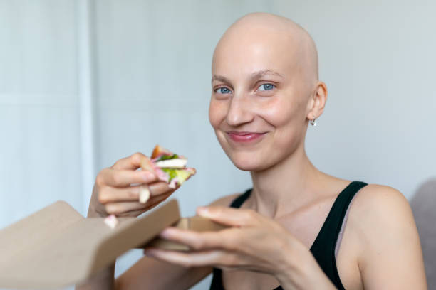 젊은 성인 아름다운 백인 대머리 면도 머리 여성 초상화는 집에서 점심 샌드위치를 먹는 즐길 수 있습니다. 유방암 생존자 영양 건강 한 다이어트 인식. 체모테라피 탈모증 - anti cancer 뉴스 사진 이미지