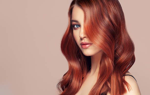 Young, red haired beautiful model with long, curly, well groomed hair. Excellent hair waves. Hairdressing art and hair care. stock photo