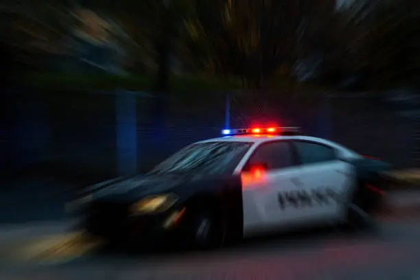 radial blur of a police car at night. Red and blue lights on top are illuminated. Car make unidentifiable. Blur radiates from lights.
