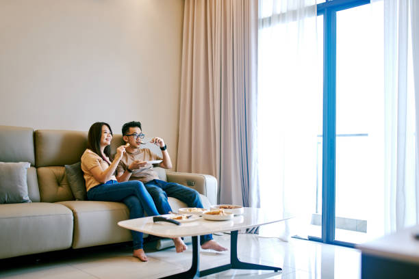 istock Beautiful Chinese Couple Eating Together at Sofa 1283392848