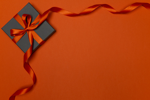 Gift box on orange color, directly above.