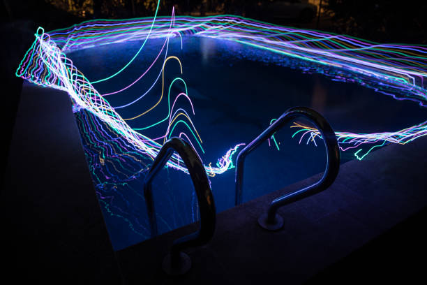 istock Pool and waterfall at night - vacation background. Colorful light decoration. Freezelight 1283394100