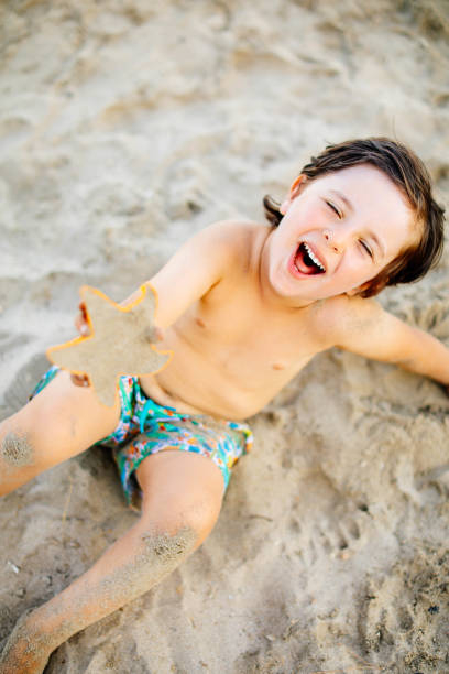 istock Happy laughing toddler boy having fun on sand 1283397947