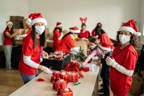 frauen ehrenamtlich durch vorbereitung von weihnachtsgeschenken für arme menschen in zeiten der pandemie - wohltätigkeit und humanitäre hilfe fotos stock-fotos und bilder