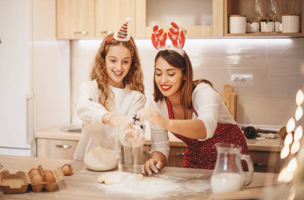 istock Older sister is telling to younger one how to bake biscuits for Santa. 1283406569