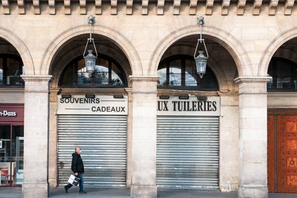 Pedestrian in front of a souvenir shop closed, during Coronavirus epidemic. Paris in France : Archs Rue de Rivoli, with a pedestrian walking in front of a souvenir shop closed, during during second lockdown of Coronavirus. October 14, 2020 curfew stock pictures, royalty-free photos & images