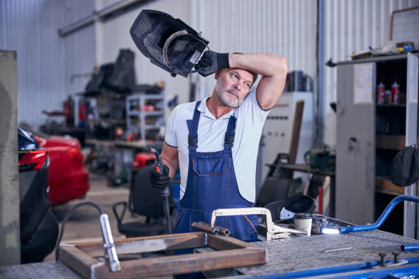 istock Handsome mechanic holding welding torch and protective helmet 1283409919