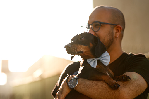 It is a picture of a man holding a dachshund.