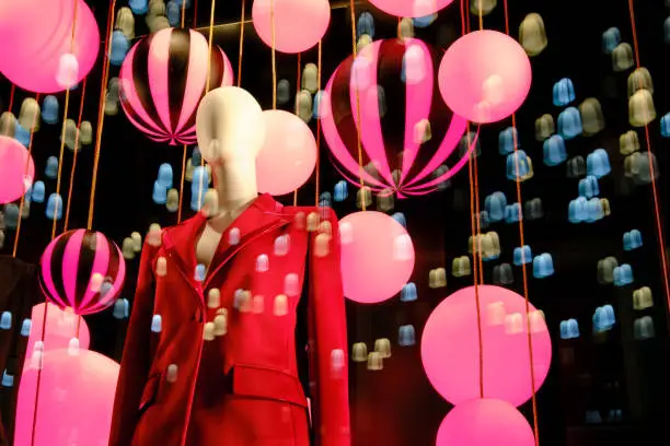 Windows clothing stores with balloons and lanterns on the eve of Christmas and new year celebrations. Woman mannequin in a suit in a clothing store