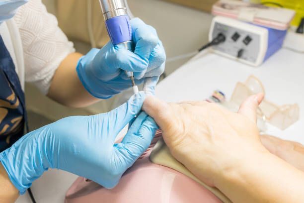 istock manicurist using electric nail drill machine before nail varnish apply. caucasian 50 years woman at manicure salon procedure. beauty treatment concept 1283414397