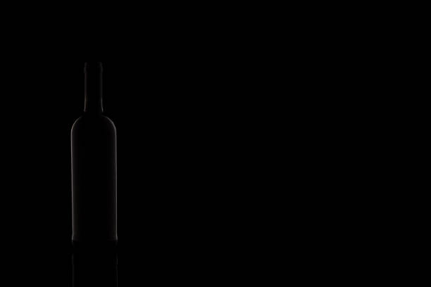 istock Wine bottle silhouette isolated on dark background. Studio photography. 1283414425