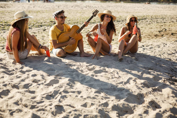 istock Young man playing a guitar for his three girlfriends 1283414546