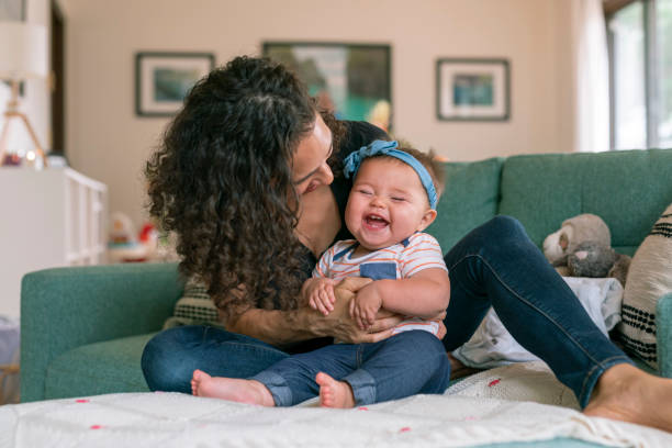 istock Adorable baby sitting up while playing with her mommy at home 1283414797