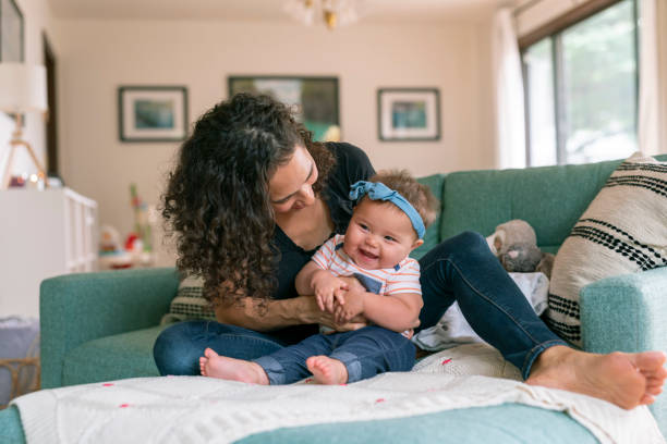 istock Adorable baby sitting up while playing with her mommy at home 1283414805