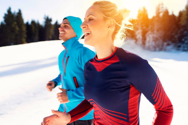 Caucasian ethnicity, young man and woman are having morning training at a ski slope. They are jogging before going for a ride.
