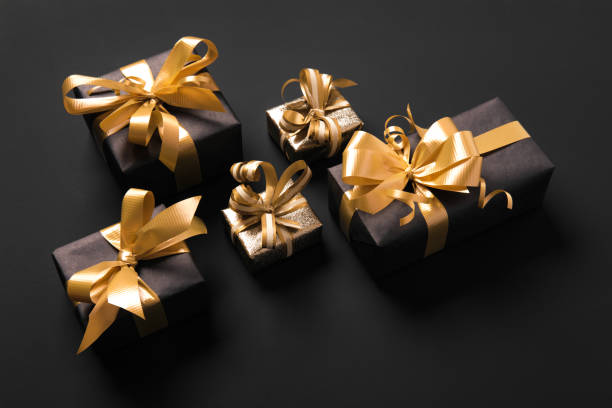 istock Festively wrapped golden gift boxes on black background. Isometric view. Holiday and black friday concept 1283415069