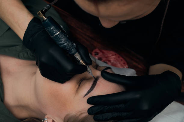 istock Permanent eyebrow makeup procedure. Eyebrow tattooing, process. The use of tools by a master for permanent eyebrow makeup. 1283415170