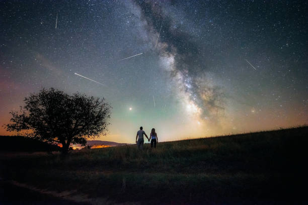 Young Couple Watching The Perseids Meteor Shower And The Milky Way Stock Photo - Download Image Now - iStock