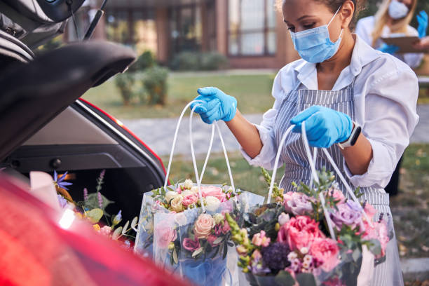 istock Mindful woman in protective equipment delivering flowers 1283418549