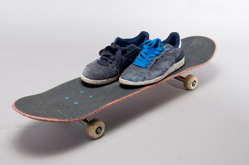 pair of gray sneakers on top of skateboard isolated on white background