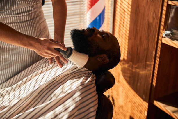 istock Barber brushing off hair around client neckline after beard trimming 1283421543