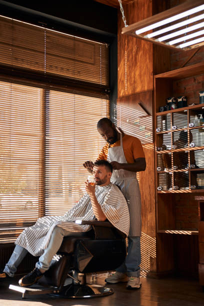 brodaty mężczyzna fryzjer cięcia włosów klienta nożyczkami - liquor store zdjęcia i obrazy z banku zdjęć