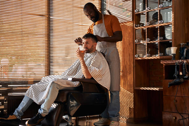 barbier dans le cheveu de client de découpage de tablier avec des ciseaux - liquor store photos et images de collection