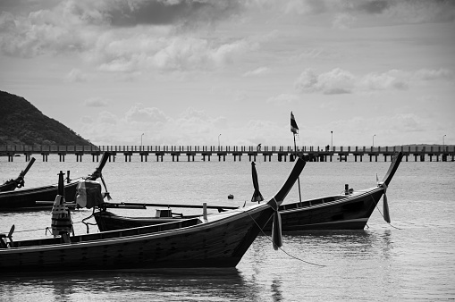 Thailand wooden long tail fishing boat at Chalong bay during monsoon season in Phuket. Black and White