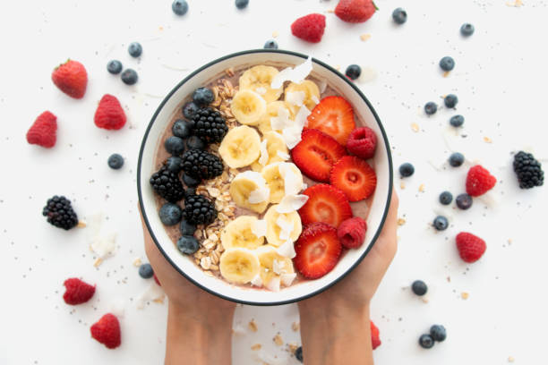 Hands Holding A Healthy Smoothie Bowl with Granola and Fresh Fruit