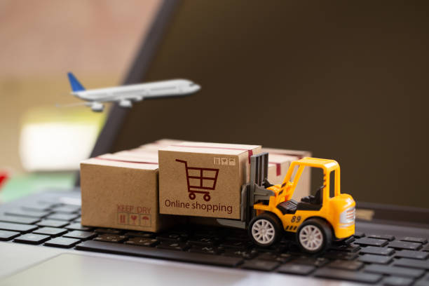 istock Logistic and cargo freight concept: Fork-lift a truck moves a paper box on notebook keyboard. depicts International freight or shipping service for online shopping. 1283436024