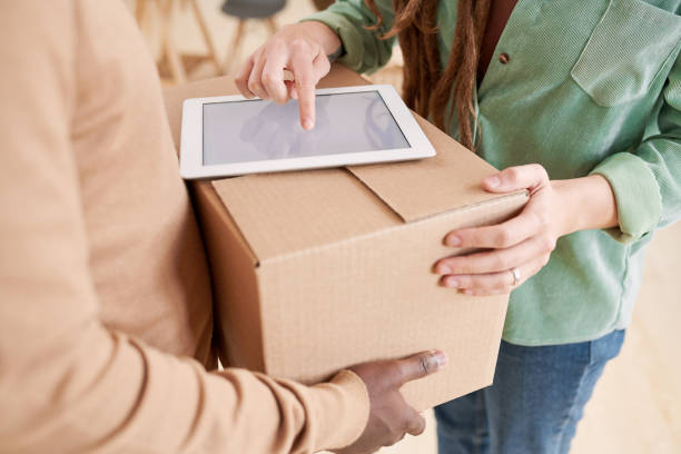 istock Close-up of unrecognizable woman making online signature on tablet while accepting box from delivery man 1283436182