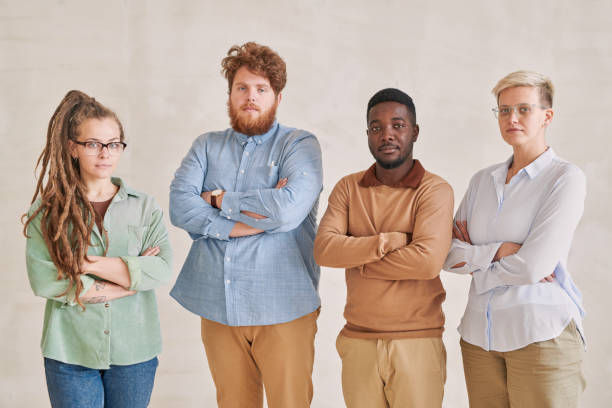 istock Group of four serious young multi-ethnic workers standing with crossed arms and looking at camera 1283436252