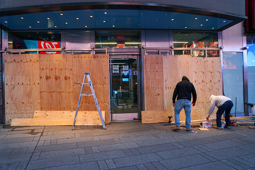 NEW YORK - October 31, 2020: Carpenters board up a storefront in Times Square in anticipation of unrest related to to the upcoming presidential election.