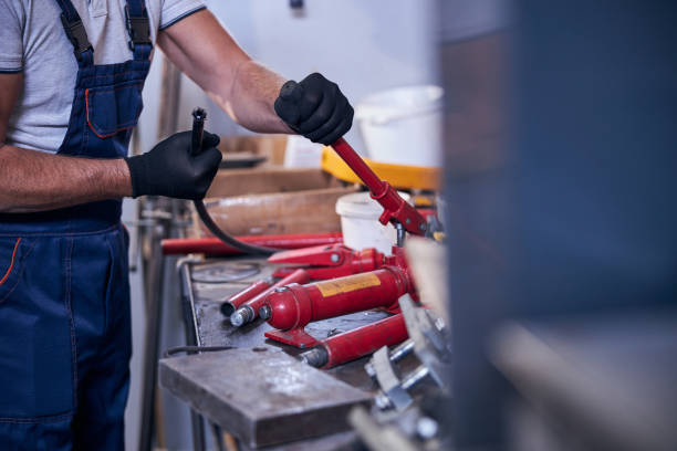 istock Male worker assembling portable hydraulic car repairing tool in garage 1283441598