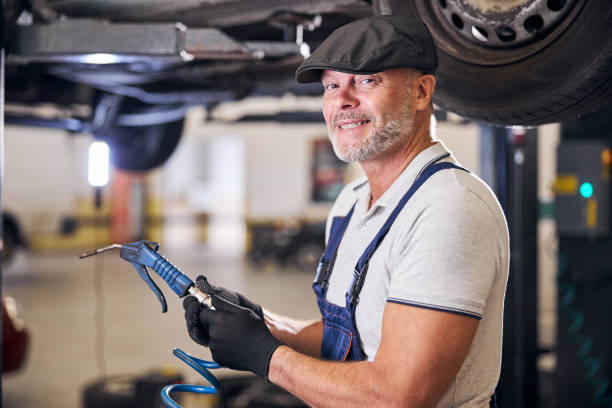 istock Cheerful auto mechanic using air blow gun at service garage 1283441600