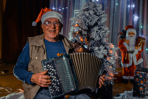Senior man playing accordion and celebrating Christmas