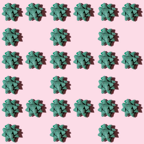 istock Seamless regular creative pattern with shiny green bow from bright ribbon with dark shadow on pink paper. Printing on fabric, wrapping paper. 1283445142