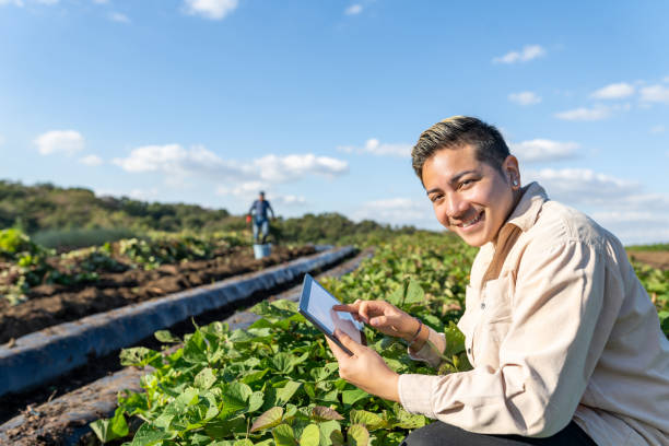 joven agricultor con tableta digital sonriendo en los campos. agricultura inteligente. - farmer rural scene laptop computer fotografías e imágenes de stock