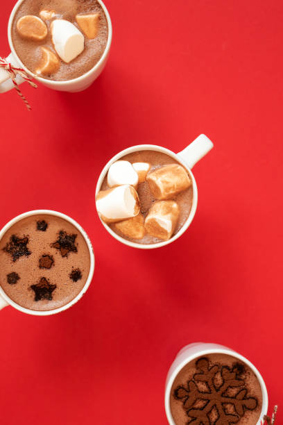 istock White cups with hot cocoa and marshmallows and spice cinnamon decor on red background, vertical. Winter holidays drinks concept 1283450375