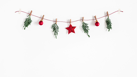 Christmas composition. Garland made of red balls and fir tree branches on white background. Christmas, winter, new year concept. Flat lay, top view