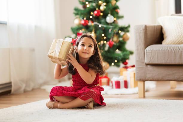 ragazza felice con regalo di natale a casa - christmas child foto e immagini stock