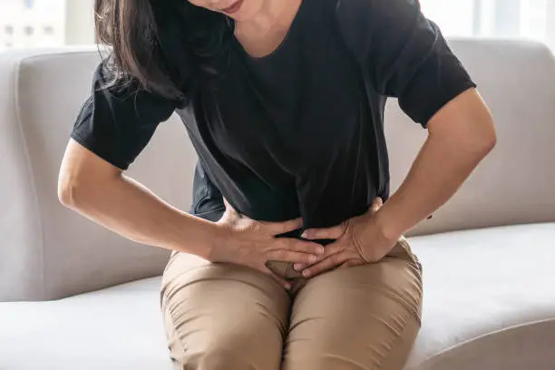 Photo of Abdominal pain in woman with stomachache illness from menstruation cramps, stomach cancer, irritable bowel syndrome, pelvic discomfort, Indigestion, Diarrhea or GERD (gastro-esophageal reflux disease)