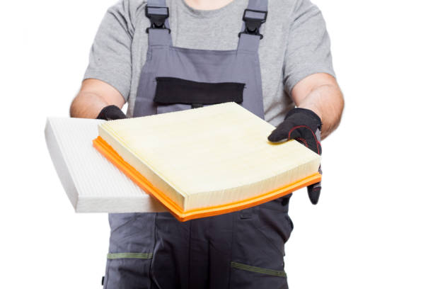 istock Car mechanic holding a new engine air filter and cabin filter, isolated on a white background 1283459719