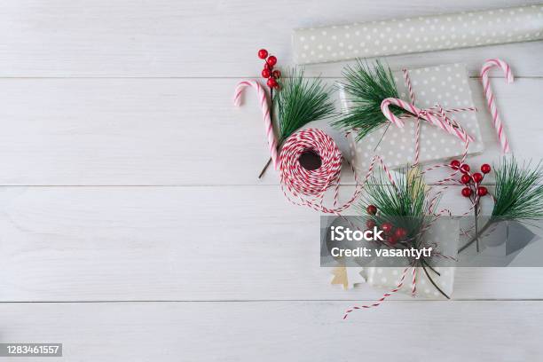 Accessories for packaging Christmas gift ,fir tree branch with red,  wrapping paper, roll of Red and white thread , christmas candy and  different wrap presents. Stock Photo