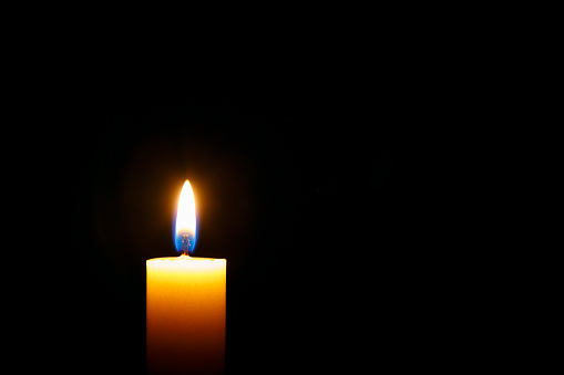 Burning candle on black background, space for text