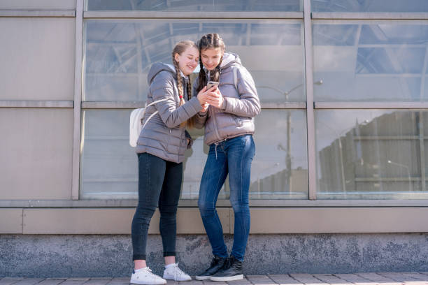 istock two girlfriends looking message on phone and smiling 1283464823