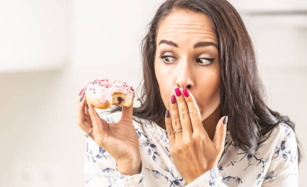 istock Oops expression on a face of a woman who has bitten into a donut in her hand. 1283466351
