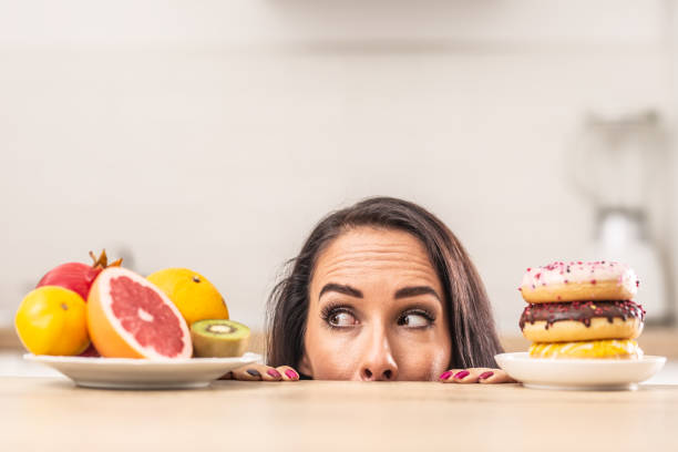istock Fresh fruit over unhealthy donuts preference by a woman in the kitchen. 1283466424