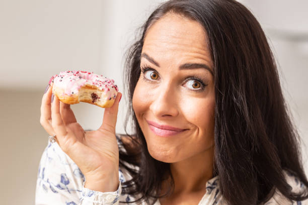 istock Guilty looking female has bitten off a doughnut. 1283466432