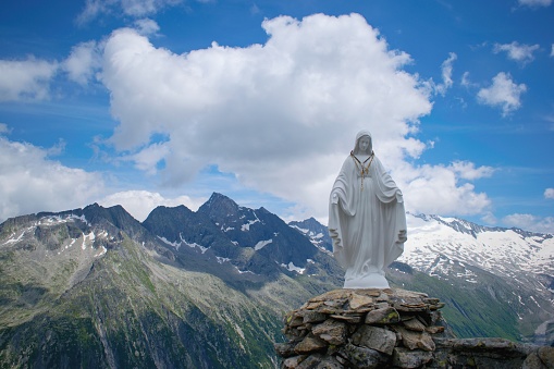 Virgin Mary statue on the mountain peak. Summer mountain scenery in  Zillertal area, Austrian Alps.